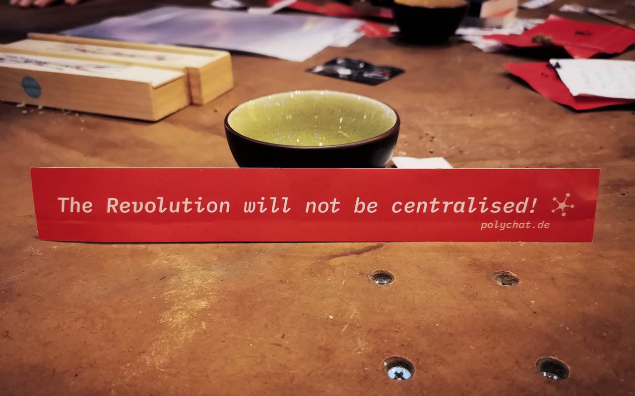 A cup of tea with a sticker stating: the revolution will not be centralised.