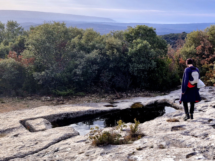 Photo de l’aiguier du Jas du Pin en Provence. Il s’agit d’un trou de 5m sur 2 sur une roche calcaire à même le sol, et d’une rigole récupérant les eaux de pluie, elle aussi à même la roche.